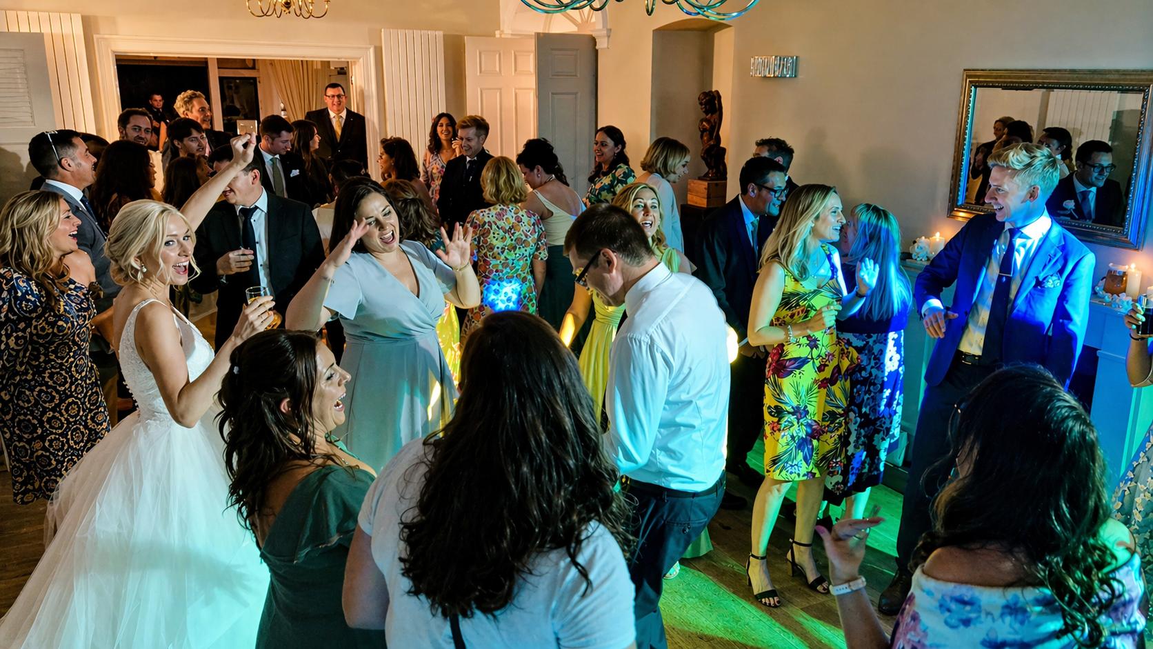 Packed wedding dancefloor with guests smiling, dancing and enjoying the evening party