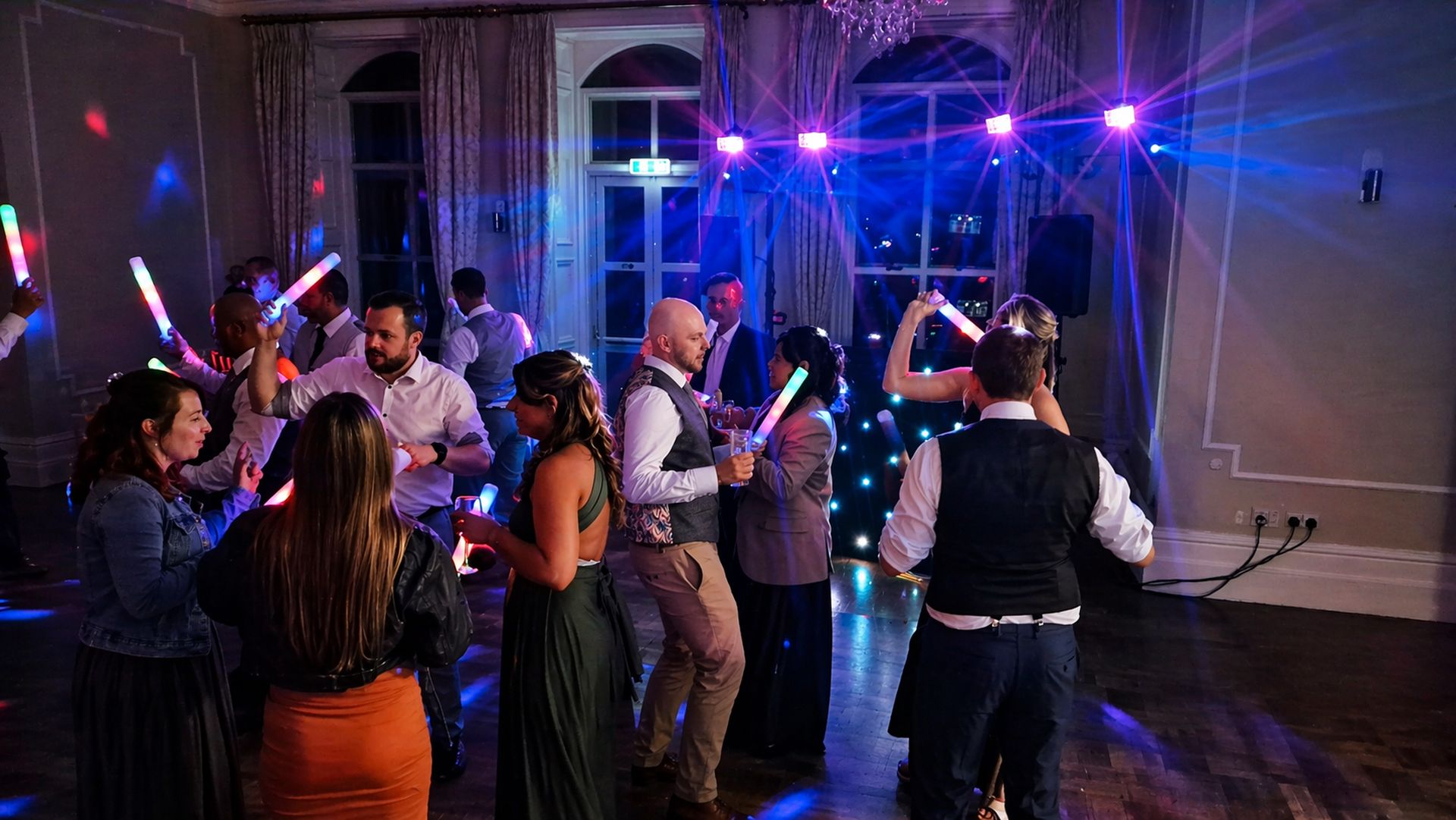 Guests dancing together at a wedding party with elegant lighting