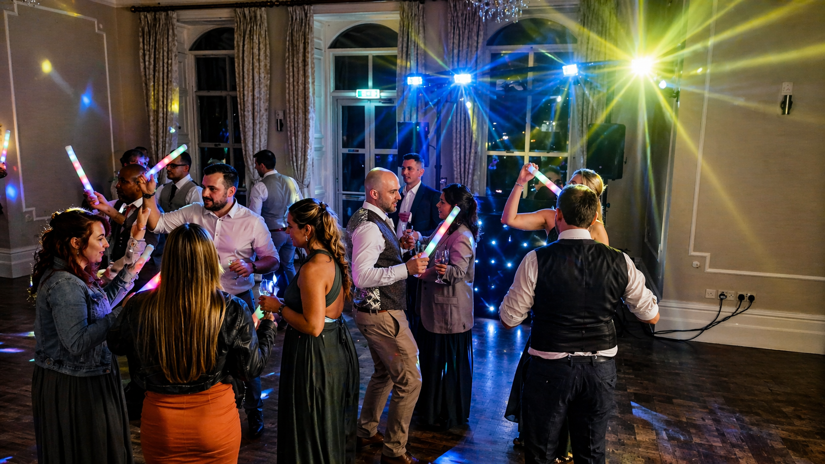 Wedding guests dancing under DJ lighting during an evening celebration